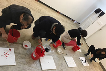 바닥에서 붓으로 뿌려가며 그리는 사진